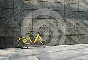 The yellows bicycle parking against at grounge modern wall