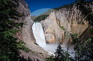 Yellowstone Falls waterfall as seen from the Uncle Tom`s Trail with a small rainbow on a sunny day
