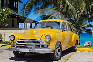 Yellwow american Oldtimer parked under palms near the beach in Varadero Cuba - Serie Kuba 2016 Reportage