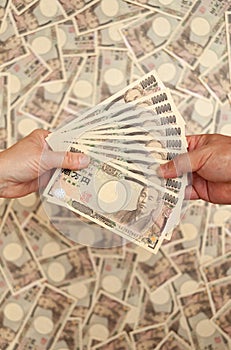 YEN - Japanese money: Hands holding paying / receiving 100,000 yen banknote.