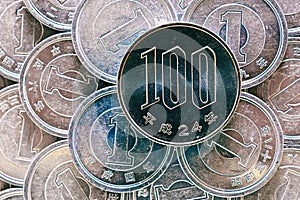 100 yen lies on a pile of Japanese 1 yen coins. Close up. View from above. Catchy money illustration. News about the economy and