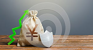 Yen Yuan money bag with a shield and a green arrow up. Safety security of investments, financial system stability. Increasing