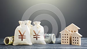 Yen Yuan money bags and residential buildings figures. Investments in real estate. Financing the construction and renovation