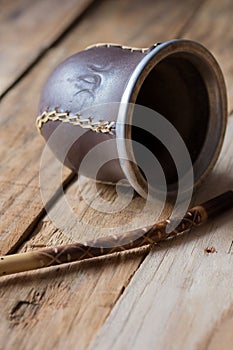 Yerba mate gourd and a bombilla straw on aged wood background, close up