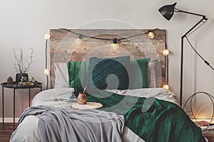 Yerba matte on wooden plate on bed with grey bedding and emerald grey blanket