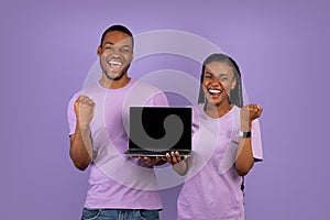 Yes. Excited black couple showing black blank laptop screen