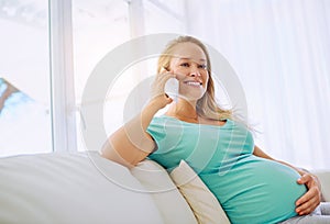 Yes Im due any time now. a pregnant woman talking on a cellphone at home.