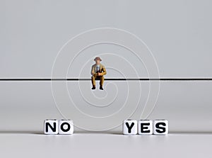 Yes or no dilemma concept. White text cube and a miniature man.