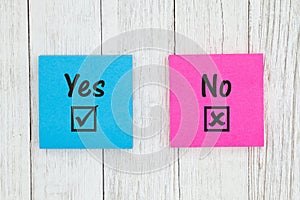 Yes and No on two sticky notes  on weathered whitewash textured wood
