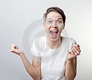 Yes. Pretty extremely happy woman celebrating her success with raised hands. Girl isolated on white background photo