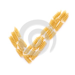 Yes tick sign symbol mark made of dry rotini pasta over isolated white background