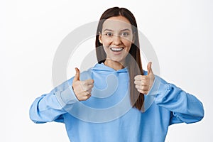 Yes, very good. Smiling woman shows support, satisfied, leave positive feedback, nod in approval and show thumbs up