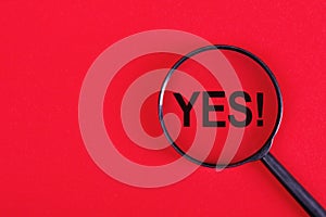 Yes word through magnifying glass on red background