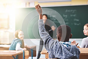 Yes you in the back there. elementary school children raising their hands to ask questions in the class.