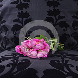 Růžový růže vlevo na černý samet sedadlo 