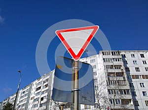 Yield Sign or Give Way against the blue sky and a multi-storey residential building. Road Markings and traffic Rules concept. Tran