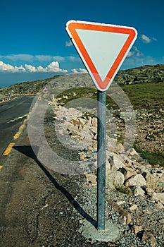 YIELD traffic signpost on roadside and rocky landscape