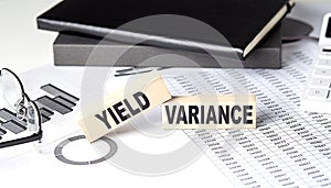 YIELD VARIANCE - text on a wooden block with chart and notebook photo