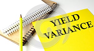 YIELD VARIANCE text written on a yellow paper with notebook photo