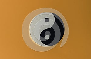 Yin-Yang symbol made of paper on orange