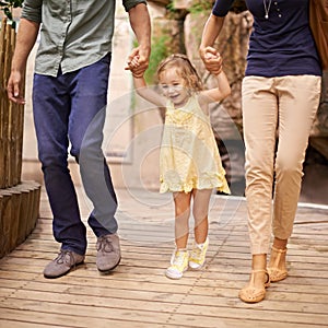 Yippee Were going on an adventure. A little girl holding her parents hands while on an outing.