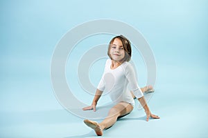 8yo girl in a white leotard doing splits, looking at the camera.