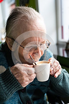 84 yo white woman drinking a cup of coffee, Tienen, Belgium photo