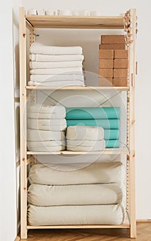 Yoga accesories, mats, blankets, pillows, etc. in nice order on a raw wood shelf