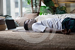 Yoga. African young man meditating on a floor and lying in Shavasana pose. photo