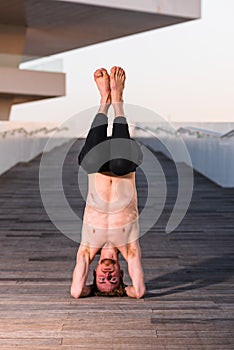 Yoga apprentice practicing sirsasana, inverted posture with the head resting on the floor