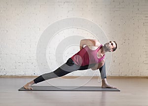 Yoga balance by legs. Caucasian fit man doing stretching on grey mat in fitness studio, selective focus.