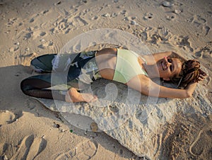 Yoga on the beach. Beautiful woman lying on the sand, practicing Supta Virasana Reclining Hero Pose. Slim body. Healthy spine.