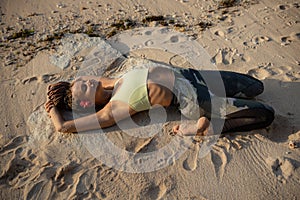 Yoga on the beach. Beautiful woman lying on the sand, practicing Supta Virasana, Reclining Hero Pose. Slim body. Healthy spine.