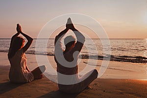yoga on the beach, couple silhouettes in lotus position