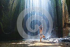 Yoga, beautiful woman practices in waterfall, body and mind harmony