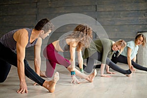 Yoga beginners exercising against grey wall, doing yoga or pilates posture.