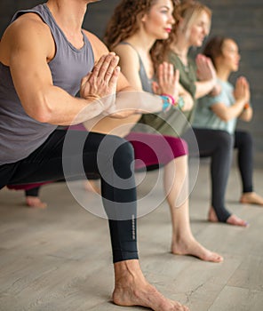 Yoga beginners exercising against grey wall, doing yoga or pilates posture.