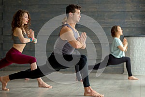 Yoga beginners exercising against grey wall, doing yoga or pilates posture.