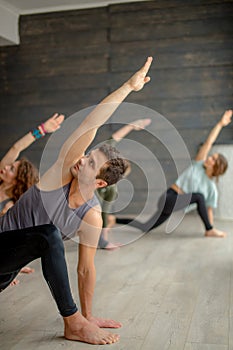 Yoga beginners exercising against grey wall, doing yoga or pilates posture.