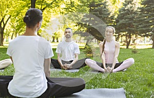 Yoga beginners listening to instructor sitting in Lotus pose