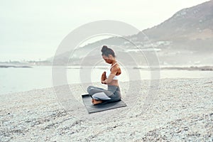 Yoga, calm meditation and woman on a beach with lotus pose, wellness and fitness. Pilates, sea and female person on sand