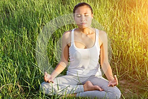 Yoga in the city: beautiful young fit woman wearing sportswear meditating, breathing, sitting with crossed legs in Half Lotus