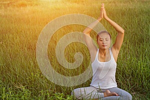 Yoga in the city: beautiful young fit woman wearing sportswear meditating, breathing, sitting with crossed legs in Half Lotus