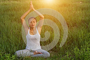 Yoga in the city: beautiful young fit woman wearing sportswear meditating, breathing, sitting with crossed legs in Half Lotus