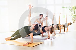 Yoga class doing side plank with trainer