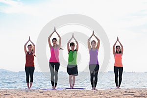 Yoga class at sea beach in evening ,Group of people doing namaste poses with relax emotion
