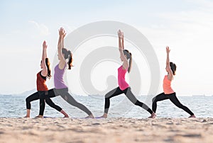 Yoga class at sea beach in evening ,Group of people doing Warrior poses with relax emotion