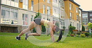 Yoga classes with headphones listening to music in the city park in the summer. Slopes and warm-up before training. A