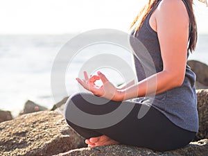 Yoga concept. Closeup woman hand practicing lotus pose on the beach at sunset