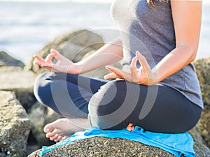 Yoga concept. Closeup woman hand practicing lotus pose on the beach at sunset